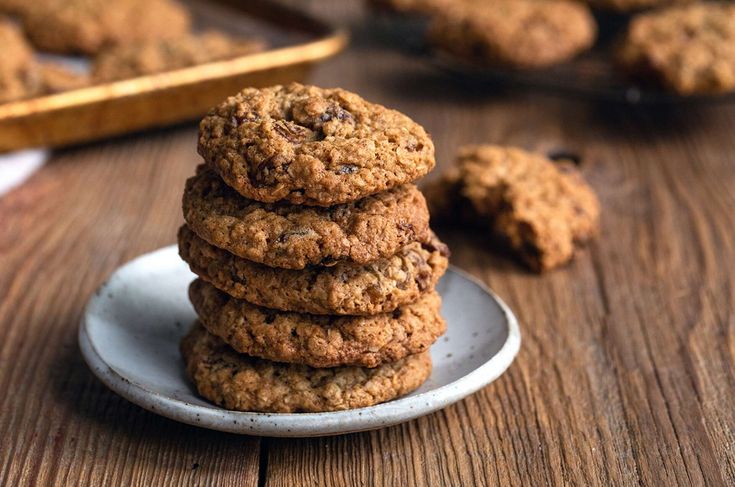 a stack of oatmeal cookies sitting on top of a white plate next to a wooden table