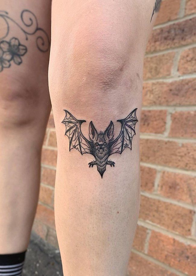 a bat tattoo on the leg of a woman