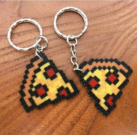 two pixel keychains are sitting on a wooden table