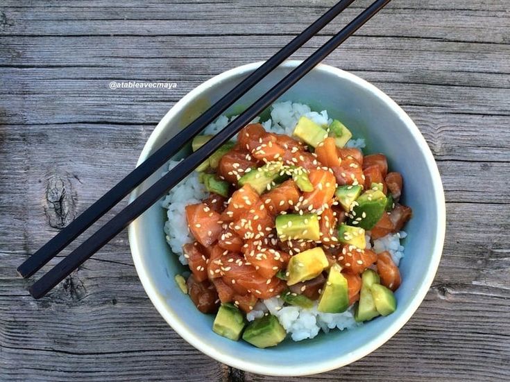 a bowl filled with rice, meat and veggies next to chopsticks