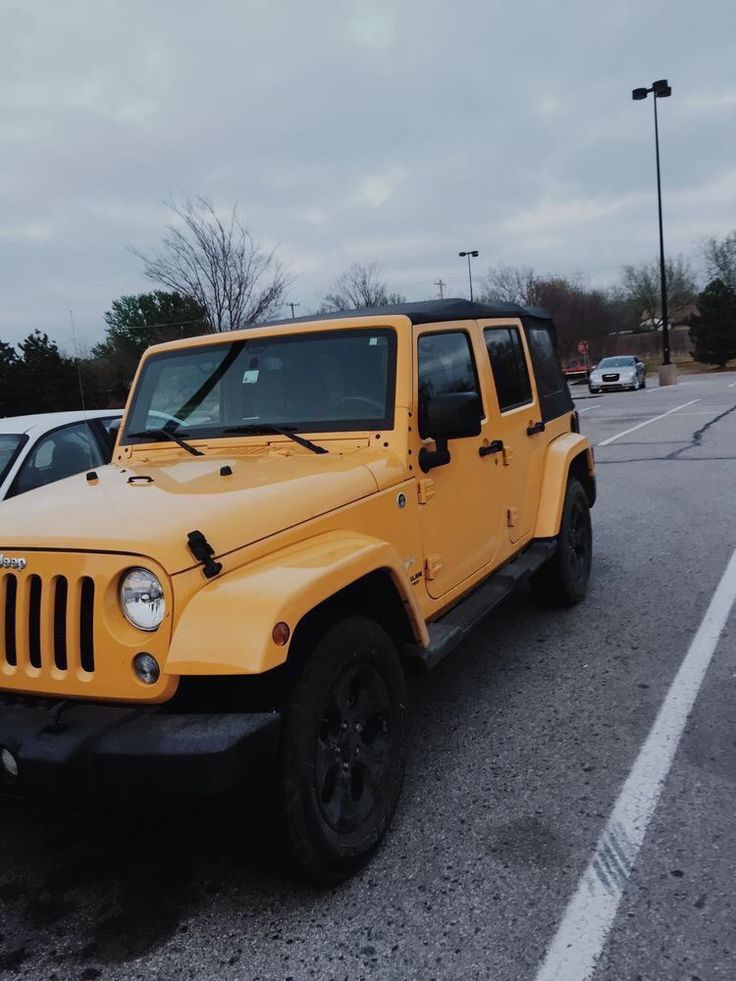 a yellow jeep parked in a parking lot