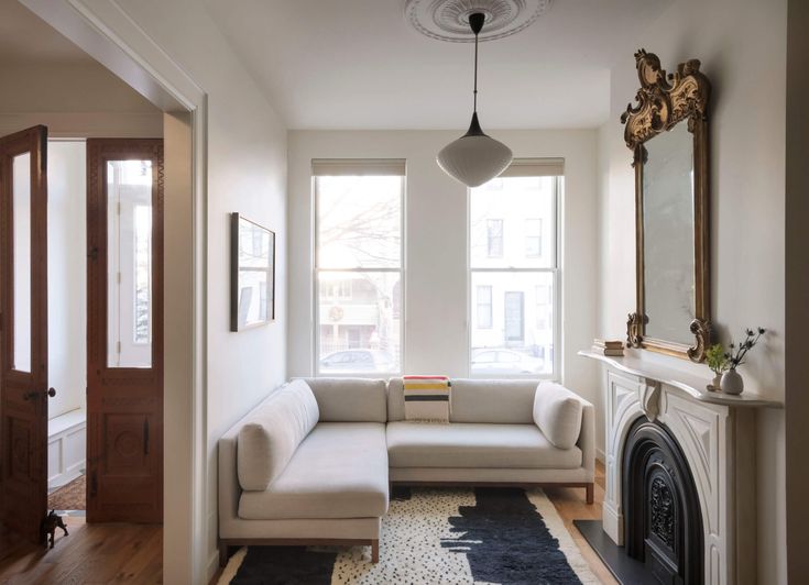 a living room filled with furniture and a fire place in front of a window on top of a hard wood floor