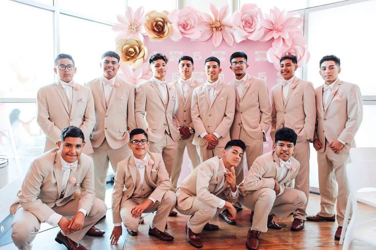 a group of men standing next to each other in front of a pink flower wall