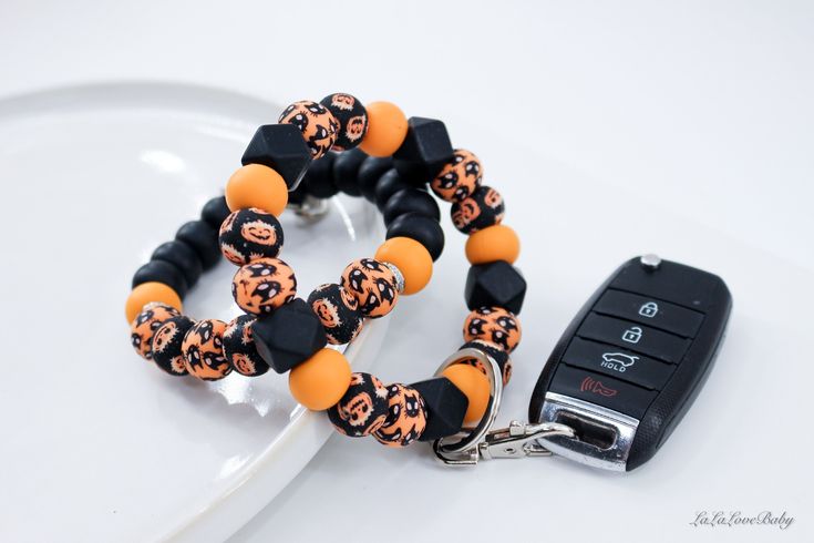 an orange and black beaded bracelet with a car keychain attached to it