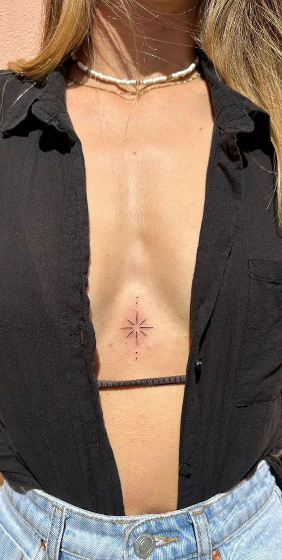 a woman's chest with a cross tattoo on her left side ribcage