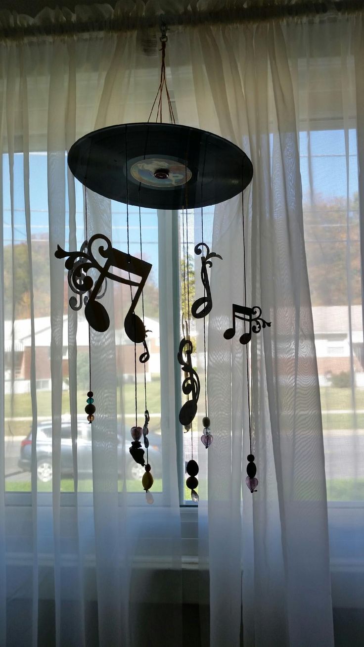 a wind chime with musical notes hanging from it's sides in front of a window