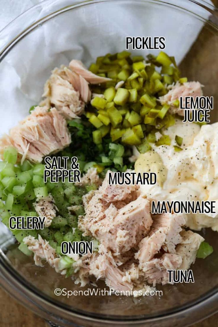 the ingredients for tuna salad in a glass bowl