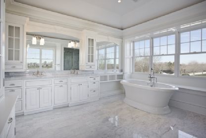 a large white bathroom with marble floors and walls, along with an oval bathtub