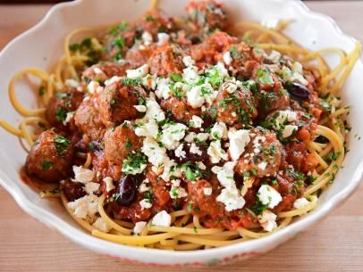 a white bowl filled with spaghetti and meatballs