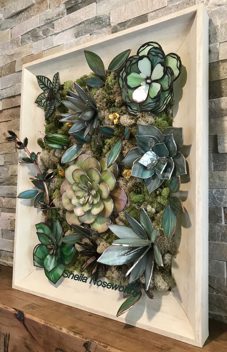 an art piece made out of succulents and moss in a white frame