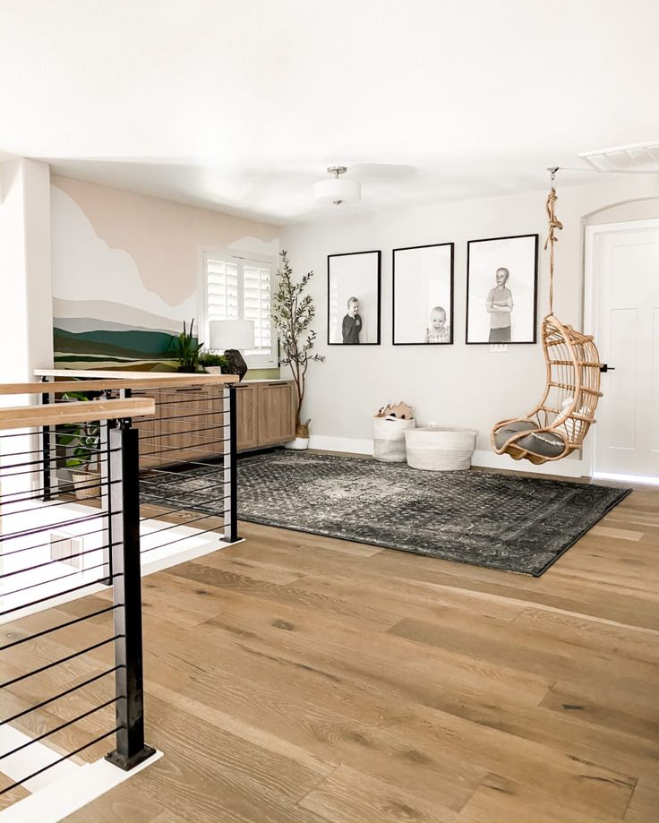 a living room with wooden floors and pictures on the wall above it's railing