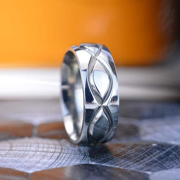 a silver ring with an intertwined design on it's side sitting on top of a table