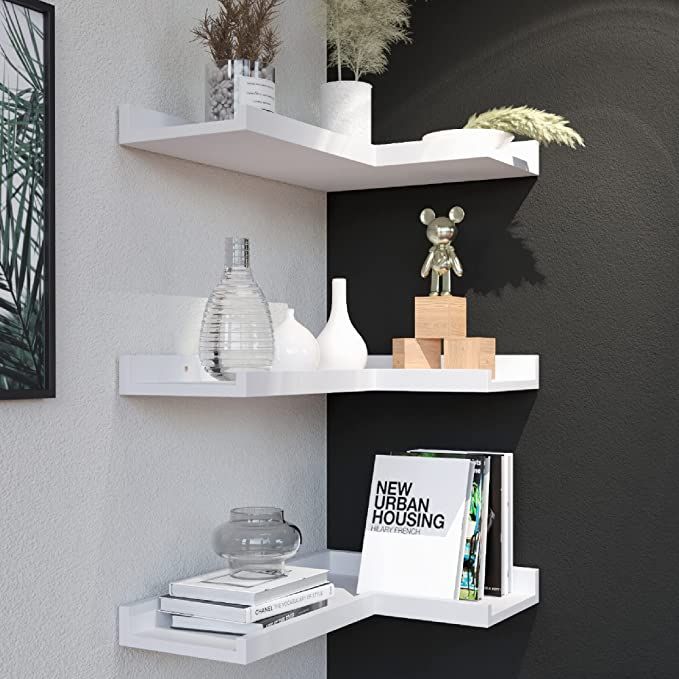 two white shelves with books and vases on them in a room that has black walls