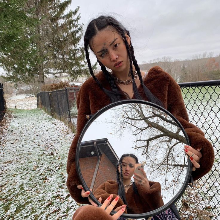 a woman holding a mirror with her reflection in it