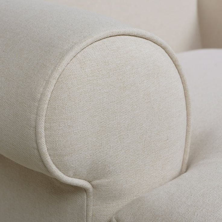 an upholstered white couch with buttons on the armrests and back end