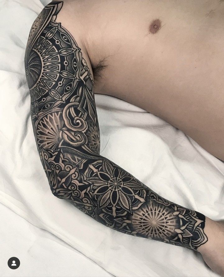 a man laying in bed with a tattoo on his arm