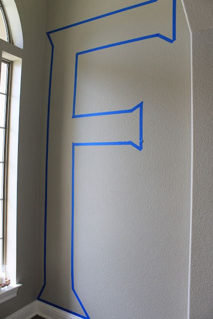 the corner of a room with blue tape on it and a window in the background