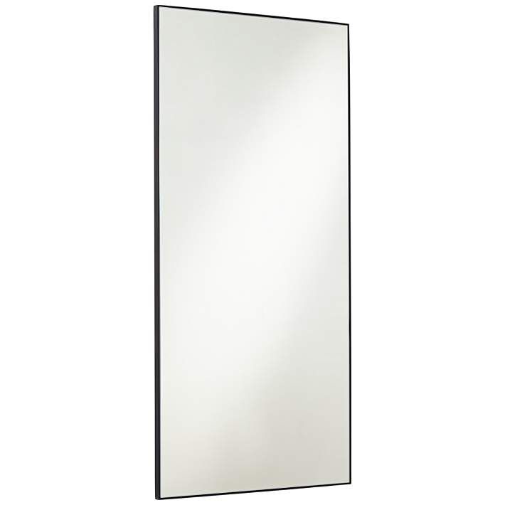 a mirror that is sitting on top of a wall next to a white wall and black frame