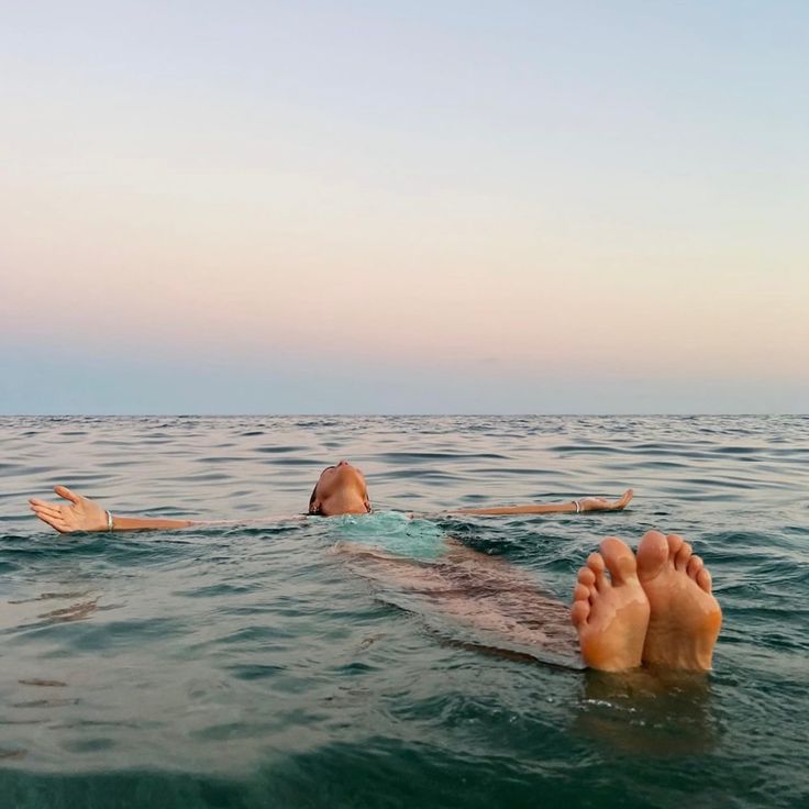 two people floating in the ocean with their feet up