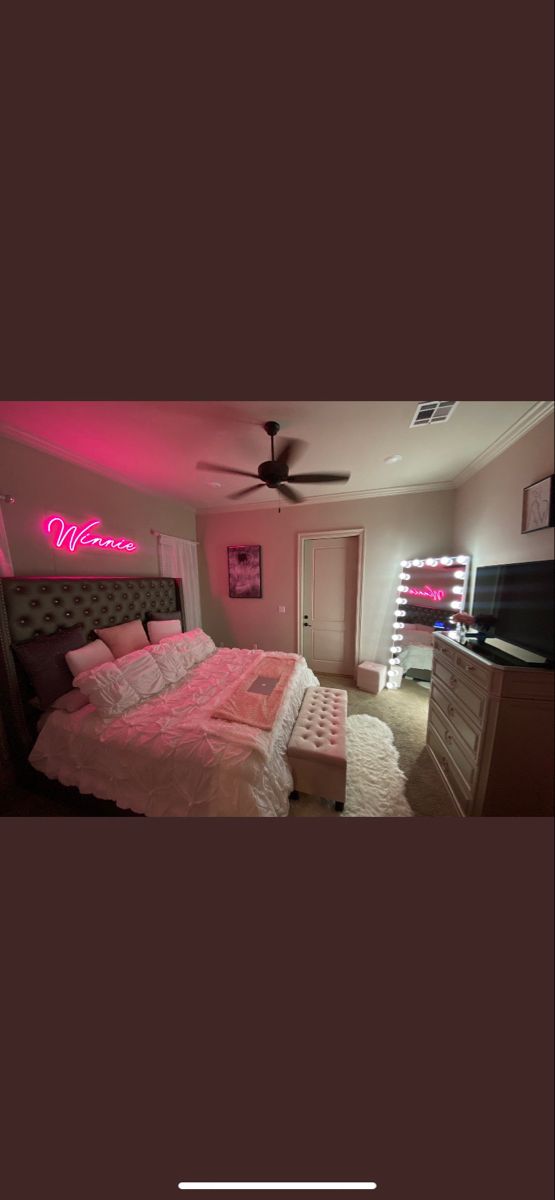 a bed room with a neatly made bed and a pink light on the wall above it