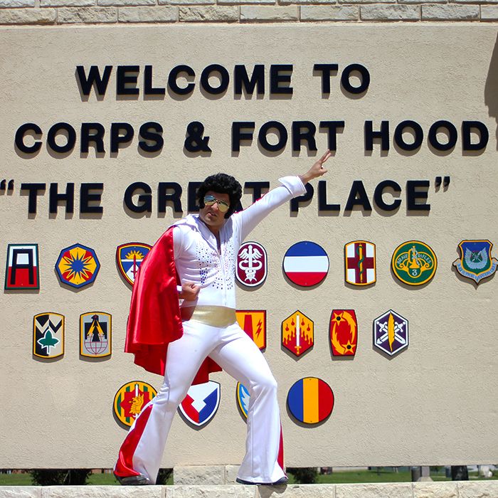 a man dressed in white and red standing on top of a stone wall with his arms outstretched