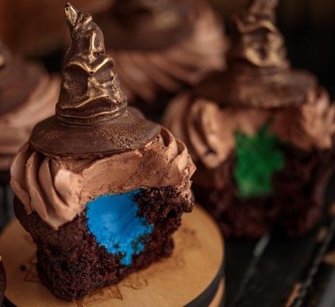 some cupcakes with chocolate frosting and decorations on top are sitting on a wooden plate