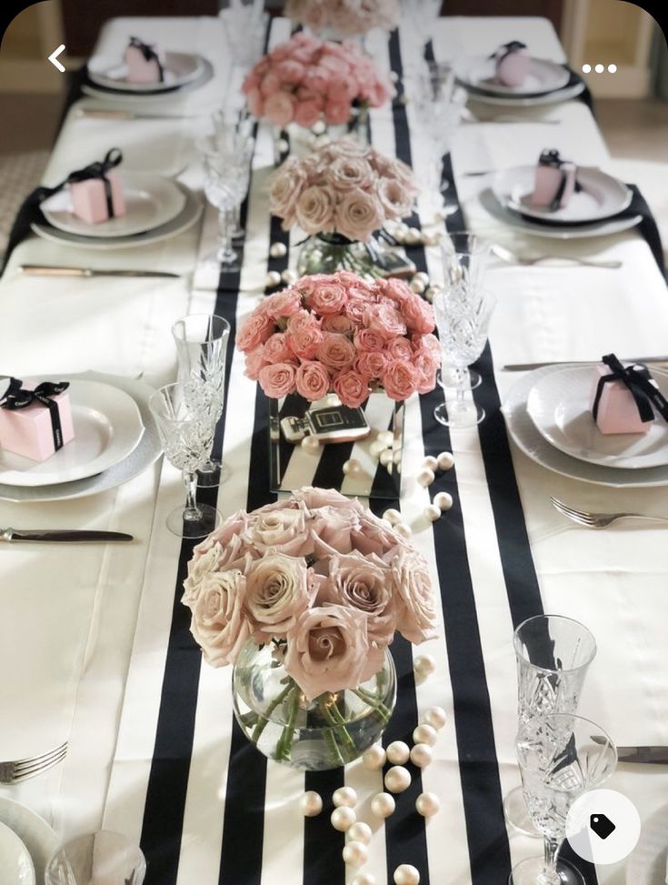 a long table with black and white striped runneres, pink flowers in vases