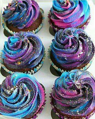 cupcakes with purple and blue frosting in a white box on a table