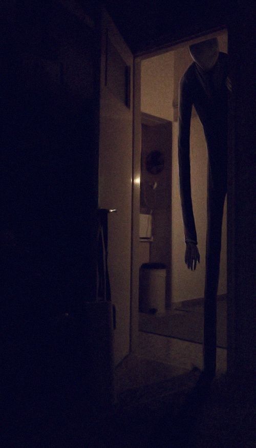 a creepy figure standing in the doorway of a dark room