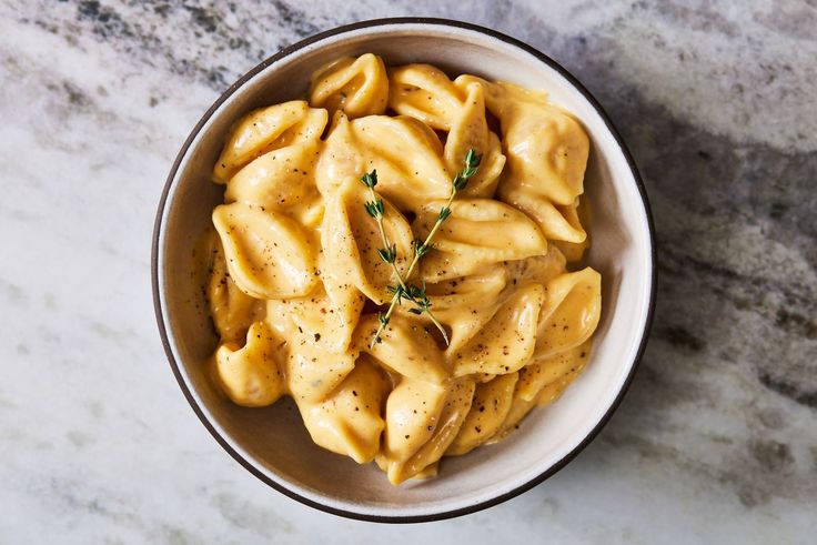 a white bowl filled with pasta on top of a marble counter