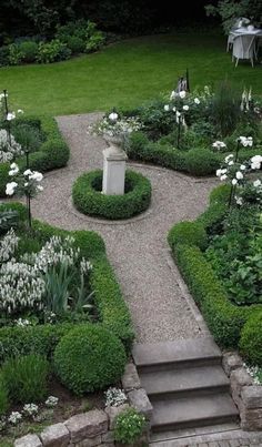 a garden with stone steps and white flowers in the center, surrounded by greenery