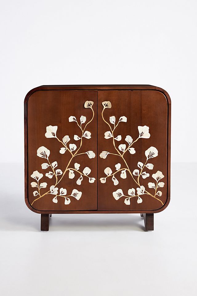 a wooden cabinet with white flowers painted on the front and side panels, sitting against a white background