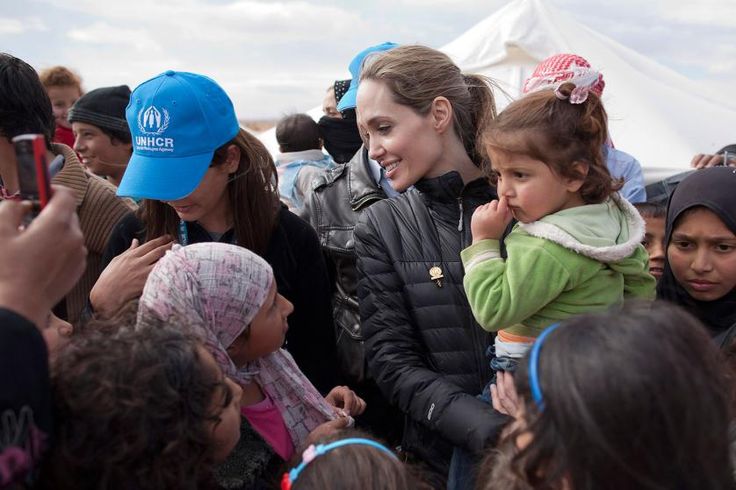 a woman holding a child in her arms surrounded by other people at an outdoor event