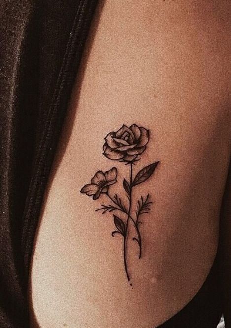 a rose tattoo on the back of a woman's left shoulder and breast area