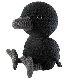 a black crocheted stuffed animal sitting on the ground