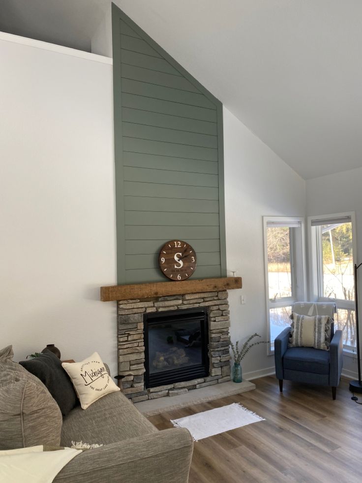 a living room filled with furniture and a clock on top of the fireplace mantel