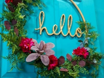 a wreath with the word hello written on it and flowers in front of a blue door