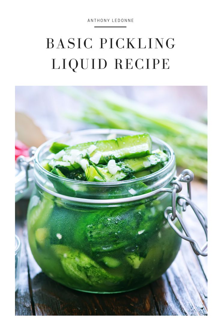 a jar filled with pickles sitting on top of a wooden table next to celery