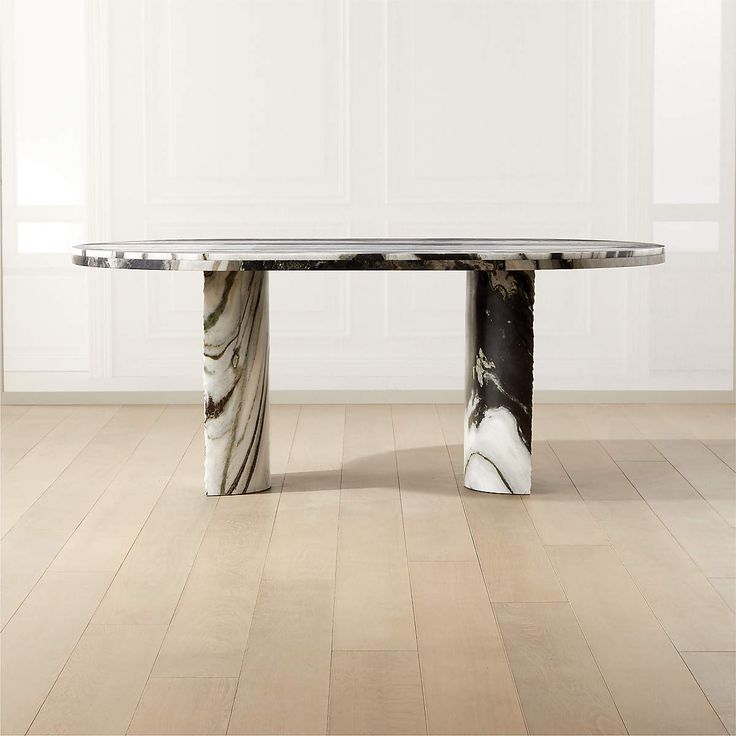 a marble dining table with black and white designs on the top, in an empty room