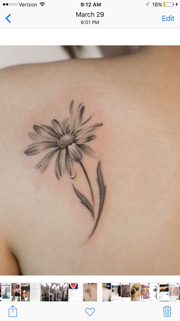 the back of a woman's shoulder with a flower tattoo on it