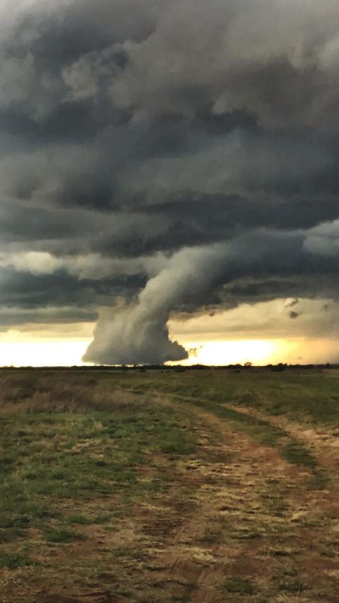 a large cloud is in the sky over a dirt road