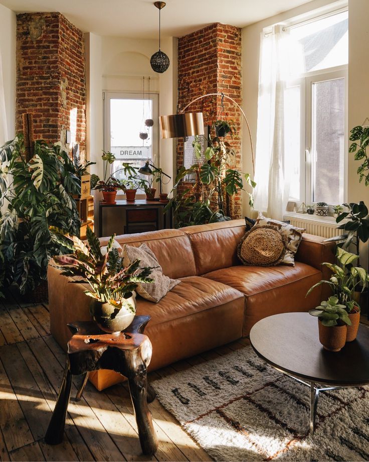 a living room filled with lots of furniture and plants on top of a wooden floor