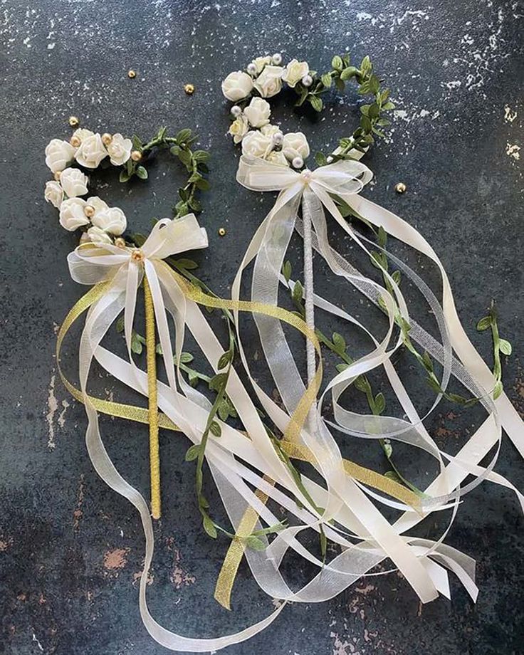 white flowers and ribbons are laid out on the ground with ribbon tied around them to make it look like they have fallen apart