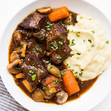 a white bowl filled with stew and mashed potatoes