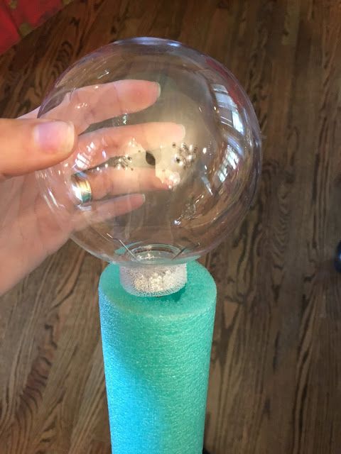 a person's hand holding onto a bubble ball on top of a blue cone