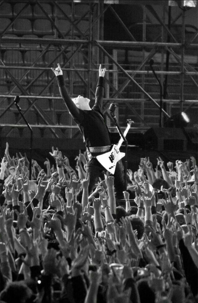 a black and white photo of a man playing guitar in front of an audience at a concert