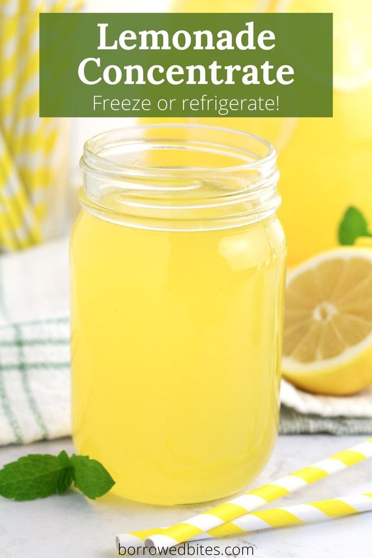 a mason jar filled with lemonade sits on a table next to sliced lemons