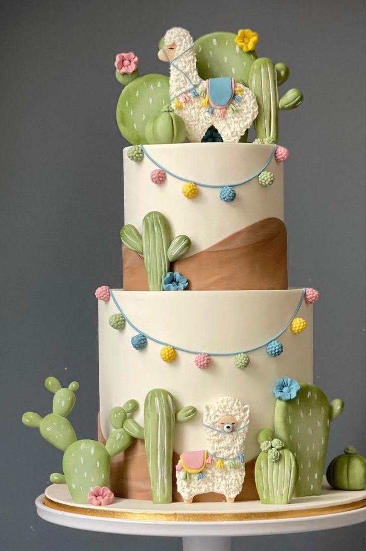 a three tiered cake decorated with cactus and llamas