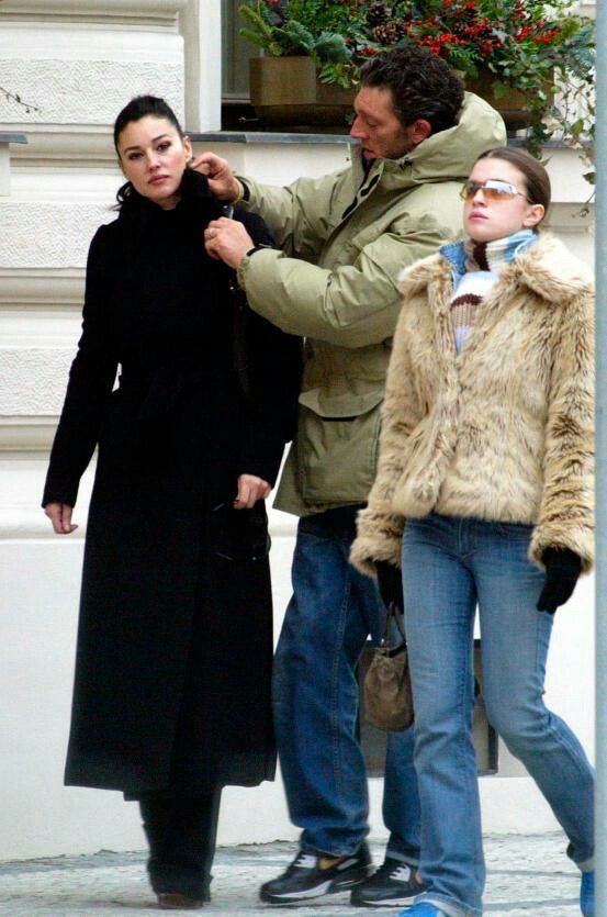 a man and woman standing next to each other on the street while one holds his tie