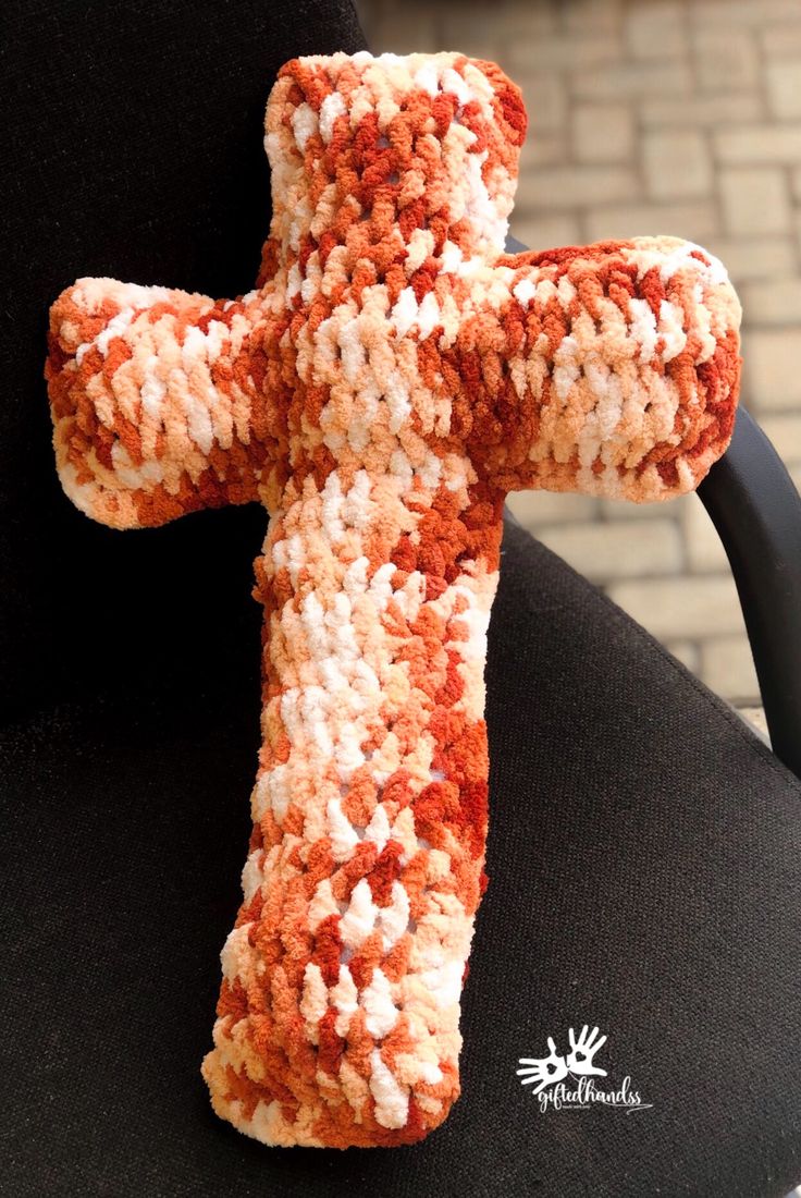 an orange and white crocheted cross sitting on top of a black office chair